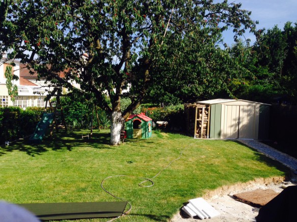 Un abri en métal avec bûcher installé dans le jardin 