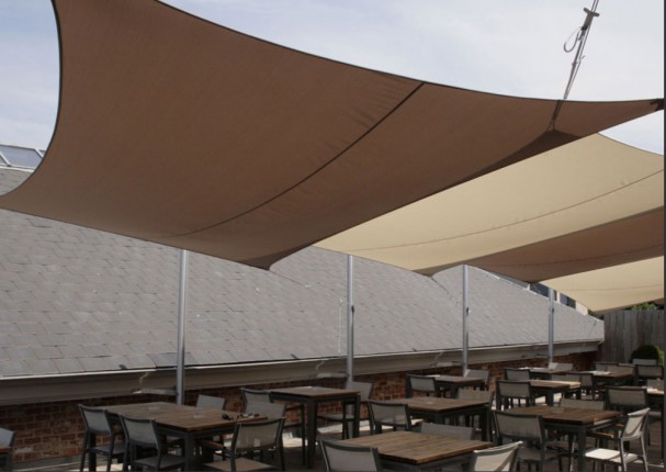 une terrasse de café ombragée grâce à des voiles d'ombrage rectangulaires