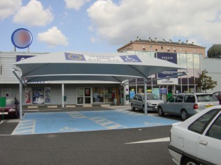 Un grand abri couvrant plusieurs places handicapées sur un parking  de grande surface