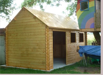 Un abri en bois dans un jardin avec un toit forte pente