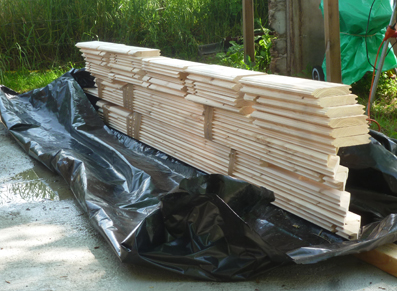 Des planches de bois disposées sur une bâche : la genèse du montage d'un abri de jardin !