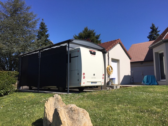 Un abri camping-car avec toit bac acier et une bâche latérale occultante